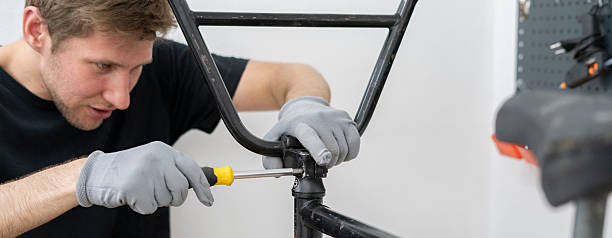 istock A person is carefully installing new bicycle handlebars in a workshop, using a screwdriver while wearing gloves. The bike rests on a stand for easy access. 2253121266