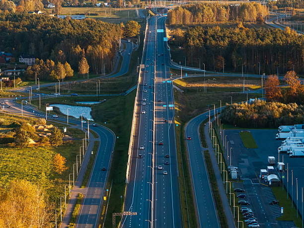 istock Aerial expressway with cloverleaf ramps and blue exit signs at dusk 2253121769