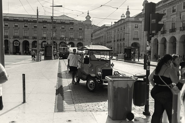 Lisbon, Portugal - July 19, 2025: A couple of tuk-uk drivers talk at the Praça do Comércio square while wainting for clients in Lisbon downtown.