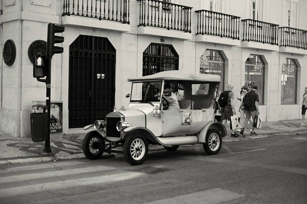 Lisbon, Portugal - May 31, 2025: A tuk-tuk driver waits for clients at a street in Lisbon downtown.