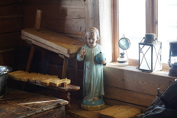 Child jesus statue stands near a window, surrounded by traditional wooden items and vintage lanterns