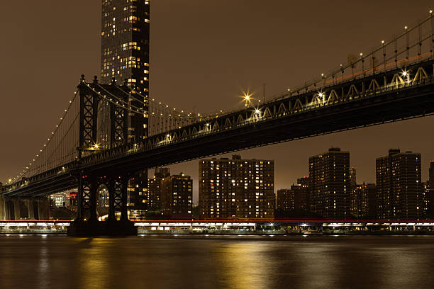 A captivating cityscape featuring a beautifully lit bridge against a backdrop of apartment buildings and the calm waters, creating a mesmerizing night scene.