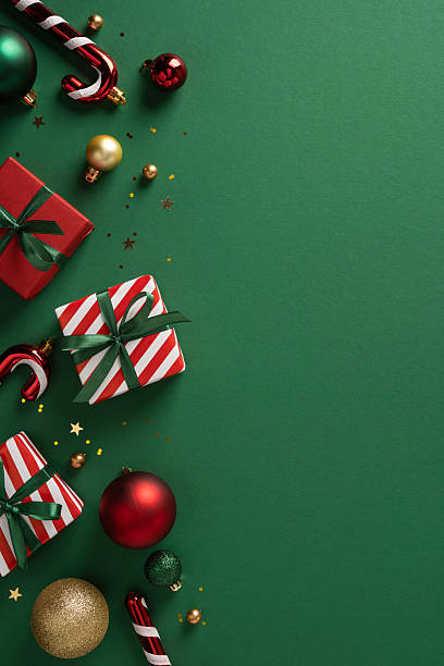 istock Vibrant vertical holiday scene featuring striped gift boxes, red and gold ornaments, candy canes, ribbons, and confetti on a green backdrop perfect for Christmas and New Year greetings 2253131272