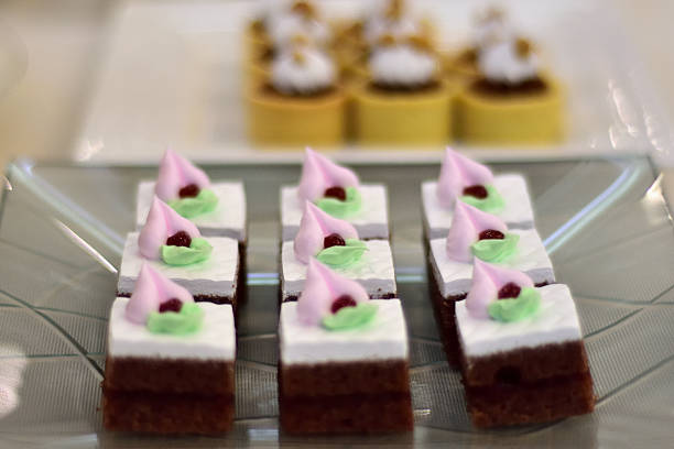 Close-up of decorative dessert squares with pink and green frosting on a glass plate.