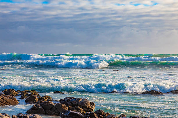 Tranquil coastline landscape with azure sky, sand, rocks, and gentle waves, South Africa