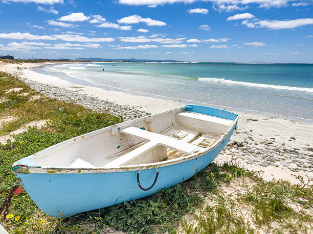 Small rowboat dinghy on a beach beneath beautiful blue azure sky