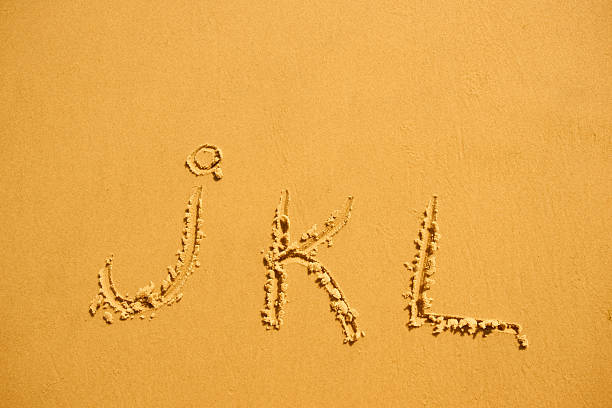 alphabet letters j k l handwritten in sand on beach