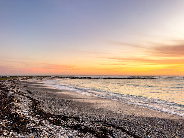 istock Dramatic Golden sunset over tranquil beach, waves lashing the pebble coastline 2253136084