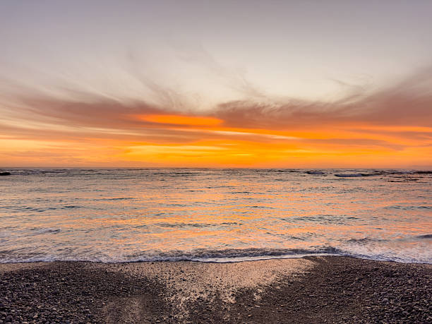 istock Dramatic Golden sunset over tranquil beach, waves lashing the pebble coastline 2253136116