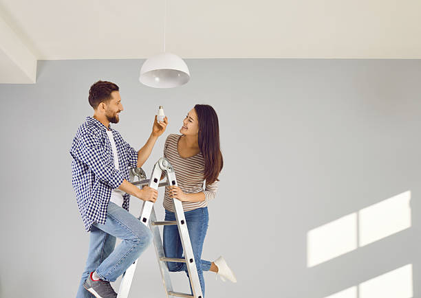 istock Cheerful young couple changing light bulb in apartment 2253136168