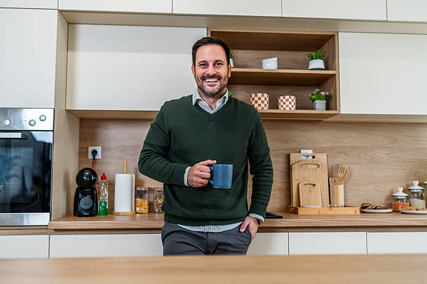 istock Young man smiling holding coffee mug in modern kitchen 2253136761