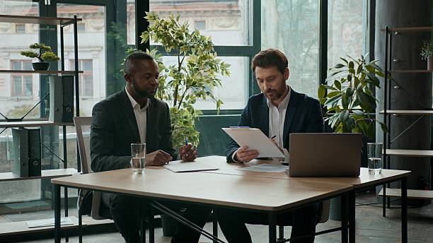 istock Two happy diverse business men team contract signing papers documents teamwork cooperation multiracial businessmen Caucasian man and African American coworkers conclude agreement partnership in office 2253139758