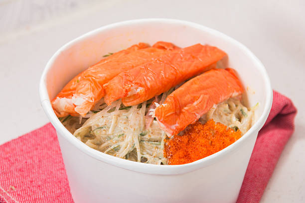 A white bowl filled with creamy salad topped with crab sticks and bright orange roe garnish.