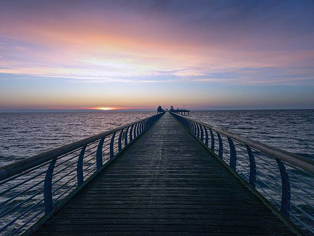 Central perspective along the Groemitz pier leading into the Baltic Sea under colorful dusk sky
