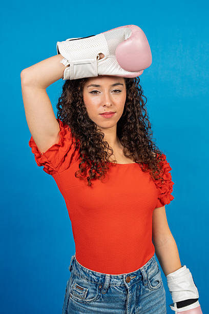 istock Empowered woman holding boxing gloves on head 2253147132