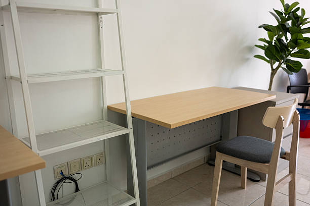 istock A workspace featuring a wooden table and chair in an empty white room 2253147185