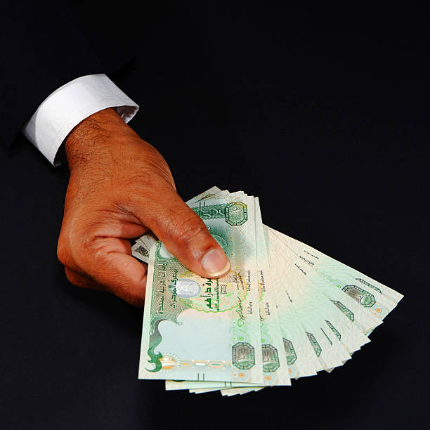 istock Hand holding UAE currency notes with black background closeup shot, Bank notes holding hand, Business and financial concept 2253156521