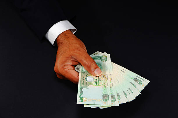 istock Hand holding UAE currency notes with black background closeup shot, Bank notes holding hand, Business and financial concept 2253156523
