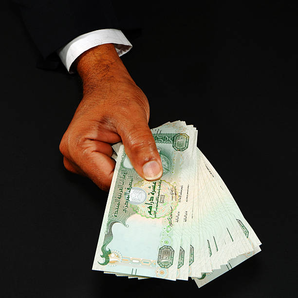 istock Hand holding UAE currency notes with black background closeup shot, Bank notes holding hand, Business and financial concept 2253156525