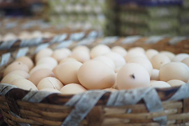 A woven basket filled with fresh eggs stands at a busy market stall.