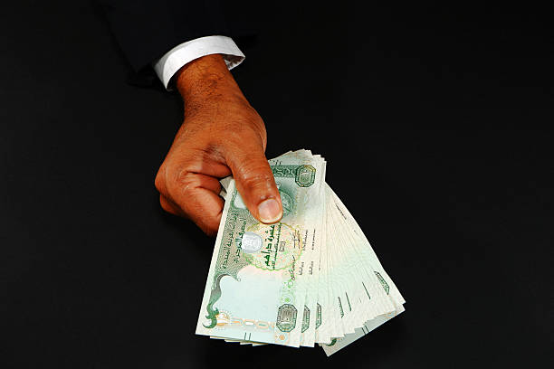 istock Hand holding UAE currency notes with black background closeup shot, Bank notes holding hand, Business and financial concept 2253156718