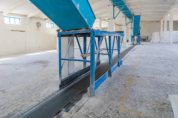 A large flour warehouse at a modern bread production facility. Sacks of flour are loaded onto a conveyor belt for transport.