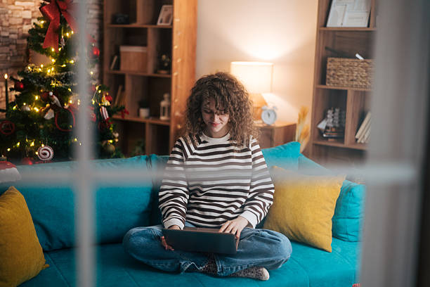 istock Young woman relaxing on sofa using laptop during holidays 2253158456