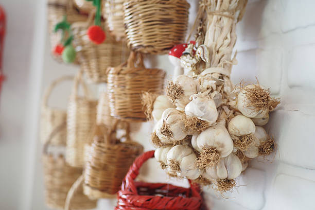 Fresh garlic hangs beside various woven baskets in a cozy kitchen.