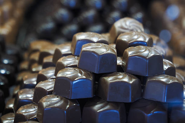 Rows of rich chocolate candies are neatly stacked for display in a shop.