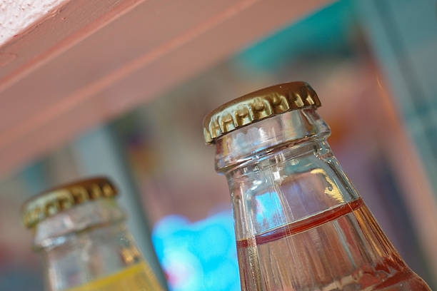 Two glass bottles with metal caps sit on a shelf, showcasing vibrant colors.