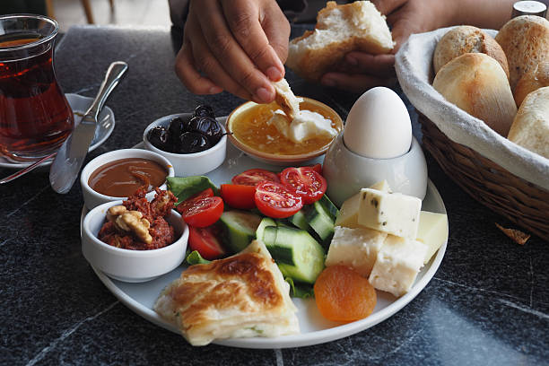 A person enjoys a traditional Turkish breakfast with assorted dishes.