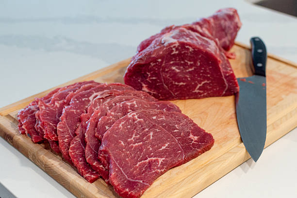 istock Slicing Raw Beef Steak on Wooden Board in home Kitchen. 2253165039