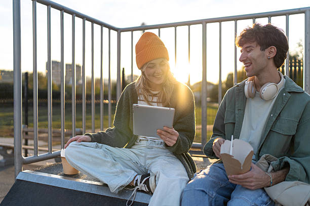 istock Young couple watching digital tablet in park at sunset 2253166284