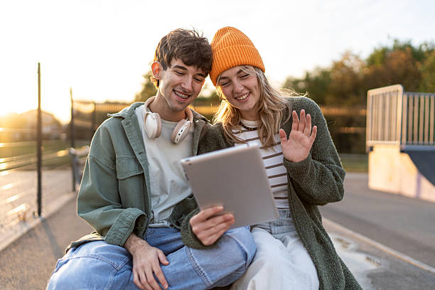 istock Smiling friends having video call with tablet at sunset 2253167616
