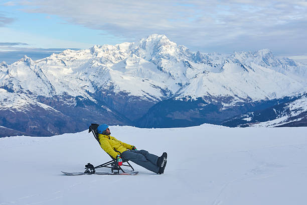 A bright alpine scene shows rows of turquoise lounge chairs on a snowy slope under a clear blue sky, inviting relaxation or a sunny day at the mountain retreat.