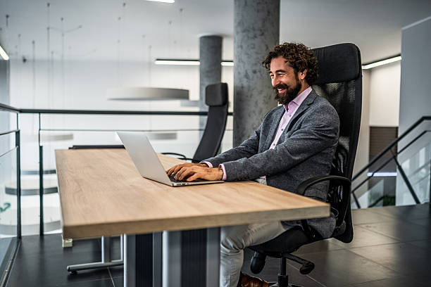 istock Happy businessman working on laptop in modern office 2253173771