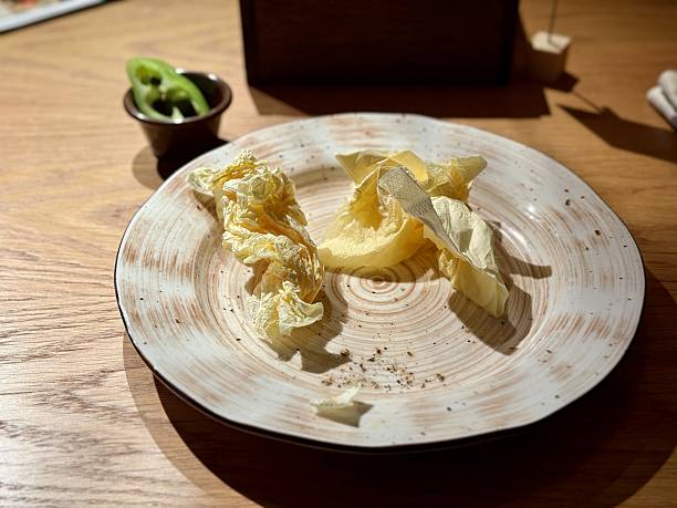 istock Plate with butter and cabbage, rustic ceramic dish on wooden table under warm ambient light, scattered crumbs and butter shavings, intimate bistro vibe, quiet after meal moment 2253174527