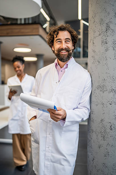 istock Scientist standing in modern lab smiling holding clipboard 2253175569