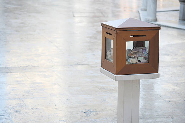 Donation box displaying various currencies in a busy area.