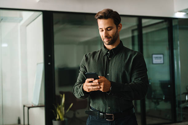 istock European ceo manager using digital technology cellphone phone mobile trade for business work online. Young Latin businessman holding smartphone telephone device standing in company office. Copy space 2253181806