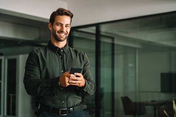 istock Middle-age manager man ceo using cell phone mobile application. Smiling Latin young businessman holding smartphone in business office working crypto online, looking at camera portrait. Copy space 2253181809