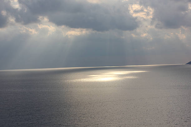istock Sun Rays Breaking Through Cloudy Sky with Reflection on the Sea 2253183222