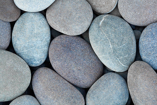 istock Pebbles stones on seashore as  texture background for design of web banner template page. many stones and they are different in color and size, dry stones illuminated by sun 2253183297