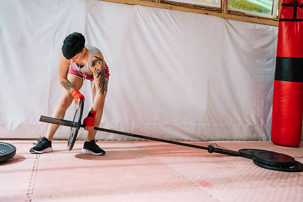 istock Woman loading weight plates onto barbell for workout 2253184254