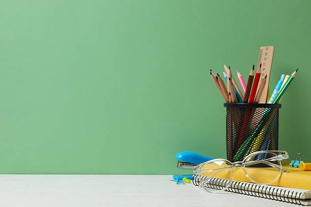 istock Colorful and modern workspace with pencil holder, notebooks and green wall 2253184319