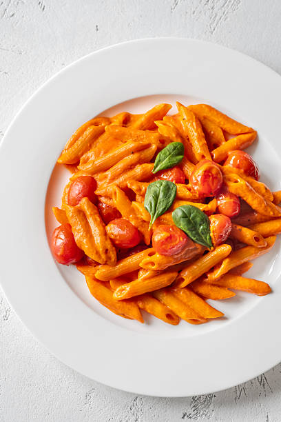 istock Penne pasta with roasted bell pepper emulsion cherry tomatoes Parmesan and herbs 2253184681