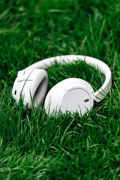 istock White wireless headphones resting on vibrant green grass 2253185254