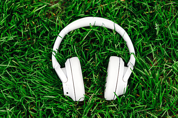 istock White wireless headphones resting on vibrant green grass 2253185259