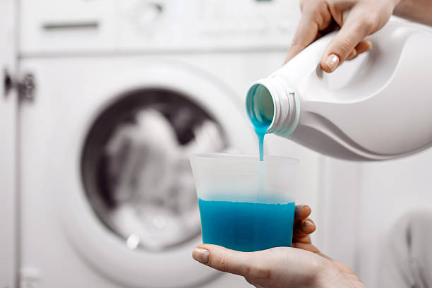 istock Hand pouring blue liquid detergent into washing machine compartment 2253185504