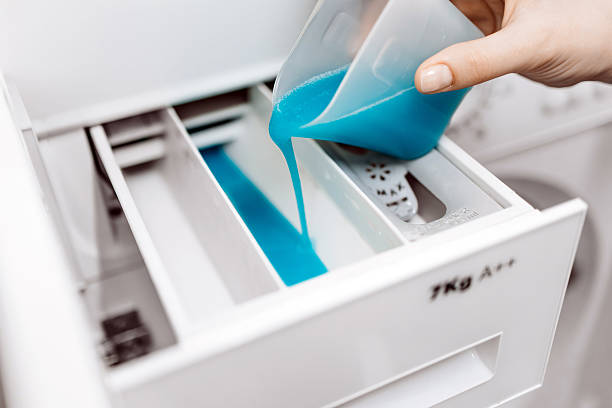 istock Hand pouring blue liquid detergent into washing machine compartment 2253185537